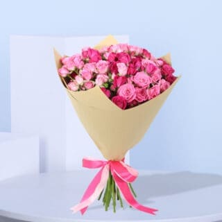 A bouquet of10 stems of pink spray roses in a brown wrap, tied with a pink ribbon.