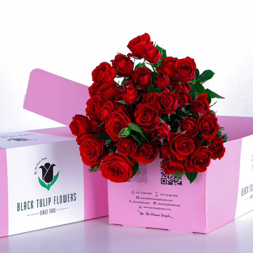 A bunch of red roses in a glass vase, paired with flower food to maintain freshness and beauty.