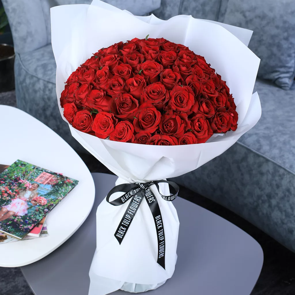 BT_FL_2017 A large bouquet of red roses wrapped in white paper and tied with a black ribbon.