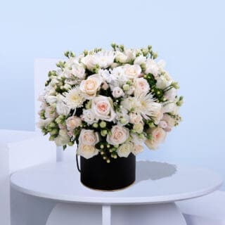 A mix of roses, spray roses, chrysanthemums, lisianthus, hypericum, and seasonal fillers in a black, easy-to-carry box.