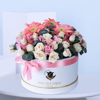 Close-up view of a beautiful combination of red and white roses arranged in a white box tied with a pink ribbon.
