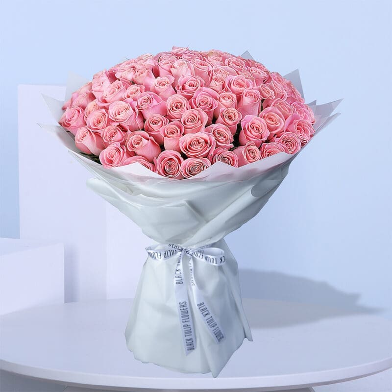 02 A large bouquet of light pink roses wrapped in white paper with white ribbons.