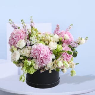 Beautiful arrangement of pink hydrangeas, white roses, and other pastel flowers in a black box.