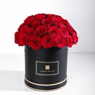 30-40 stems of vibrant red roses elegantly arranged in a black round box with "Flowers For You" written on it.