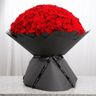 A huge bouquet of red roses beautifully wrapped in a sleek black wrap.