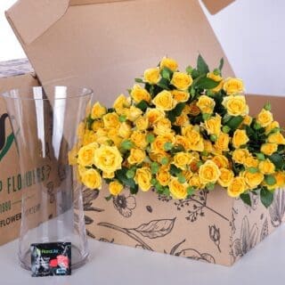 A bunch of yellow roses in a glass vase, accompanied by flower food to keep them fresh and vibrant.