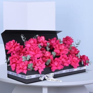 A rectangular black box filled with 28-30 pink roses and eucalyptus, beautifully tied with a white ribbon.