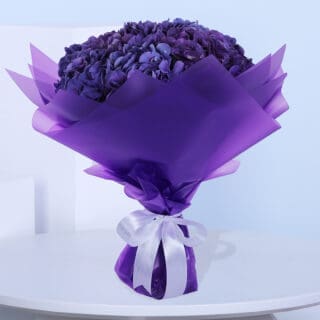 A bouquet of purple Hydrangeas in a luxury purple wrap tied with a white ribbon.
