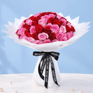 Elegant mix of red and pink roses, wrapped in white and tied with a black ribbon.