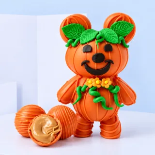 A pumpkin-shaped teddy bear alongside white chocolate treats, perfect for festive celebrations and gifting to loved ones.