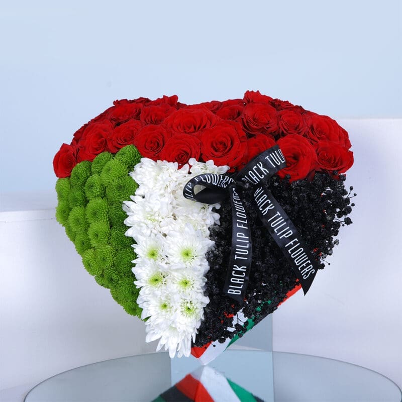 Heart shape flower arrangement with UAE flag colors and tied with a black ribbon