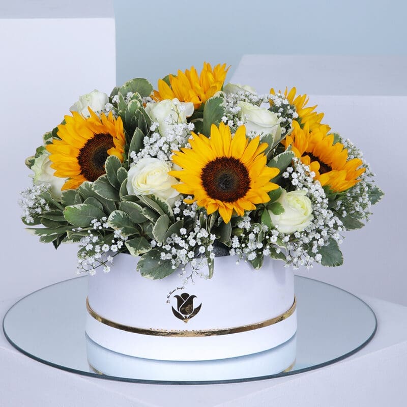 01 A circular box filled with a bouquet of bright yellow sunflowers and white roses.