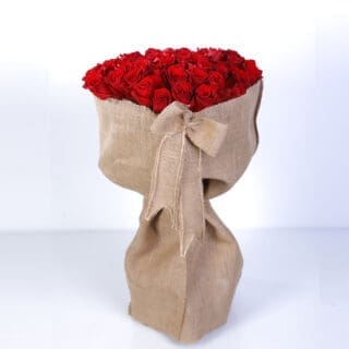 A large bouquet of 50 red roses wrapped in burlap with a burlap ribbon.