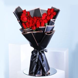 A beautiful bouquet of red roses wrapped in elegant black and gold paper.