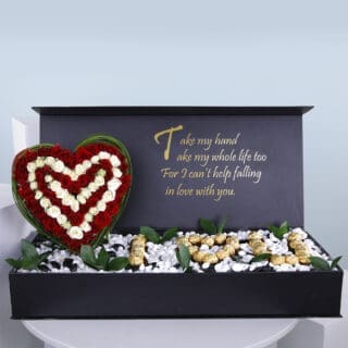 A gift box with a heart-shaped red and white rose arrangement, "I L U" spelled with Ferrero and a romantic poem inside.