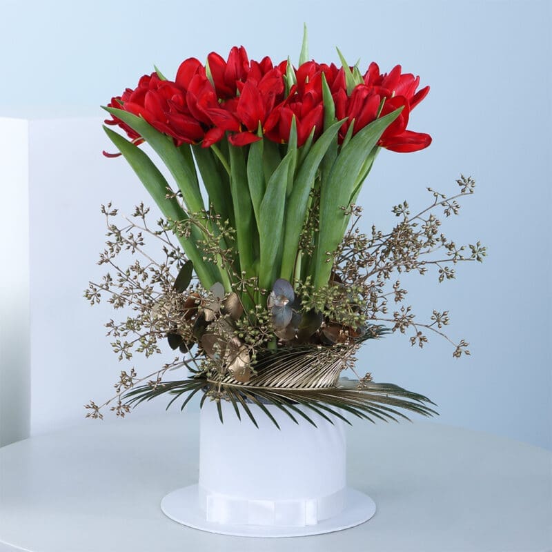 01 A bouquet of red tulips in a white vase with golden leaves and branches