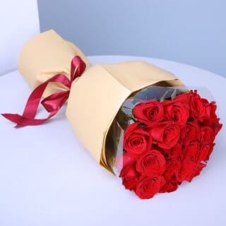20 vibrant red roses wrapped in soft peach paper and finished with a maroon ribbon.