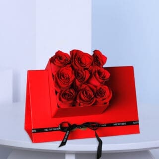 A top view of 9 red roses in a red triangular gift box.