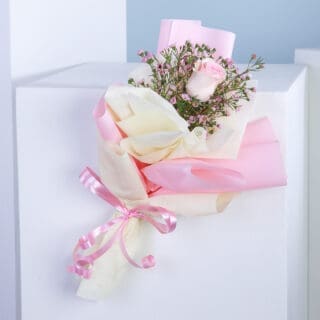 A bouquet of flowers with a pink bow on a white surface.
