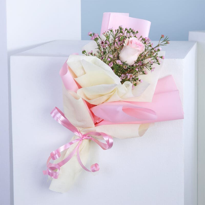 A bouquet of flowers with a pink bow on a white surface.