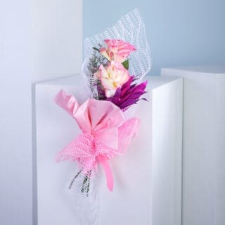 Bouquet of pink and yellow roses with purple flower accent.
