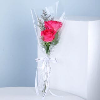 A bouquet of pink roses wrapped in clear plastic cellophane paper.