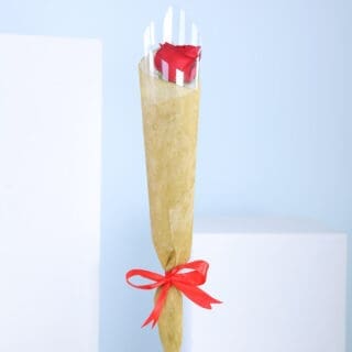 A wrapped bouquet of red roses tied with a red ribbon.