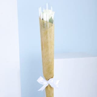 A bouquet of a single white roses wrapped in brown paper with a white ribbon.