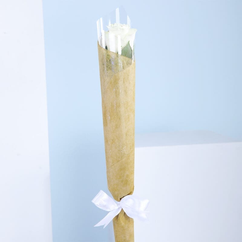 01 A bouquet of a single white roses wrapped in brown paper with a white ribbon.