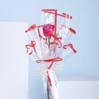 A single rose wrapped in cellophane with red ribbons.