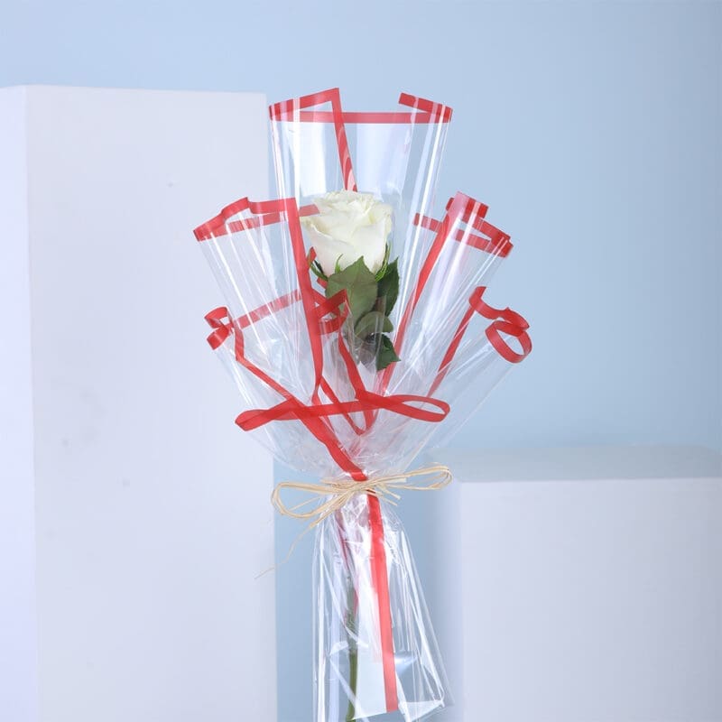 01 A single white rose in clear wrapping with red ribbons.