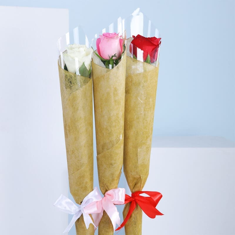 01 Three wrapped bouquets with pink, white, and red roses, tied with coloured ribbons against a blue background.