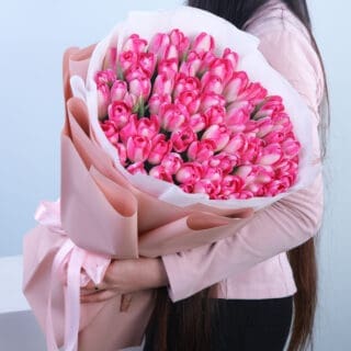 A handcrafted, hand-held bouquet of 100 pink tulips