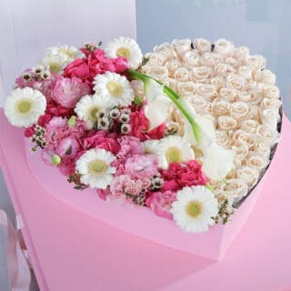 A heart-shaped arrangement of white roses, pink hydrangeas, white daisies, and white calla lilies in a pink box.