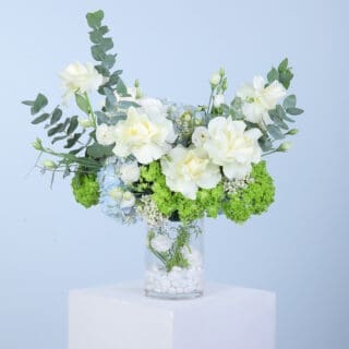 White hydrangea with greens in a glass vase