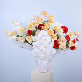 A beautiful arrangement of peach roses, white anthurium, phalaenopsis stems, gerberas, and greens in white wrap
