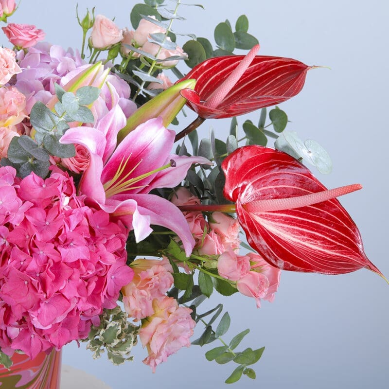 2 A colourful floral arrangement with a mix of pink, red, and white flowers in a pink modern vase.