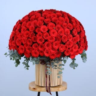 A luxurious gift of love: a massive bouquet of 300 red roses in a woven basket with eucalyptus accents.
