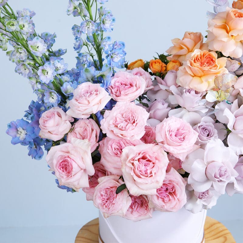 04 - Patel Mixed Flower Box Elegant flower box featuring 20 Ohara roses, purple roses, peach roses, peach baby roses, and delphinium for a stunning display.