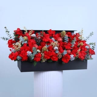 Christmas flower arrangement with red roses and pine cones.