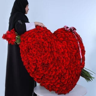 A large heart-shaped arrangement of red roses with a bow and arrow.