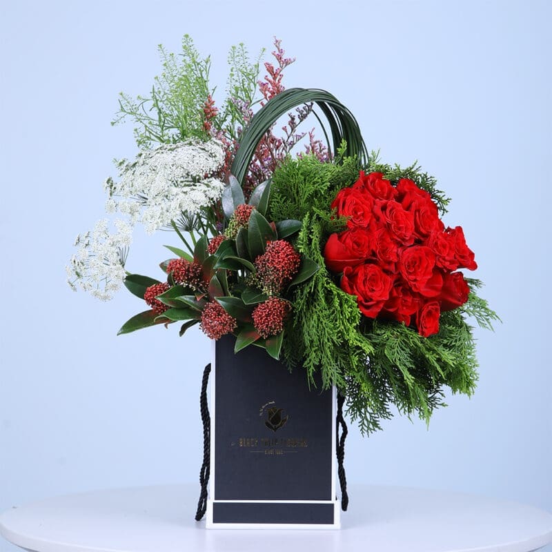 Valentine flower box overflowing with red roses, evergreens, and white blooms, perfect for spreading love