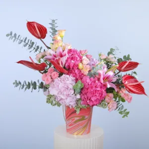 The centerpiece features a beautiful combination of pink hydrangeas, deep pink hydrangeas, vibrant red anthurium, delicate baby roses, graceful lisianthus, and lilies. They are arranged with lush greenery and presented in a chic, modern box, making it an ideal gift for any special occasion.