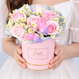 Elegant arrangement of blush pink roses with delicate white tanacetum blooms in a premium floral box.