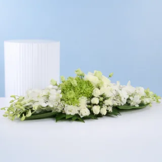 Elegant event table florals arranged with white orchids, green chrysanthemums, white roses, spray roses, layered textures, and lush decorative foliage.