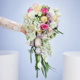 Elegant waterfall-style bridal bouquet showcasing soft pastel shades and delicate textures, carried by a bride during her walk down the aisle.