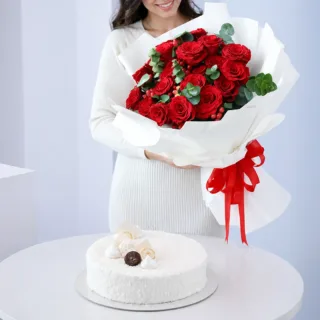 Premium floral arrangement featuring red roses, green fillers, and berries combined with a 1 kg Raffaello Cake for online gift delivery