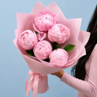 Bouquet of bloomed hand-tied peony flowers, wrapped beautifully as a present.
