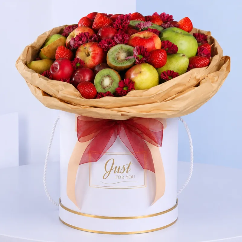 Decorative arrangement of assorted fruits and fresh flowers in an elegant white round box presentation.
