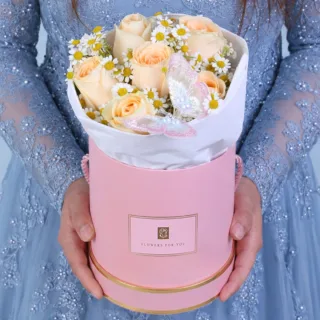 A peach rose gift box with delicate white flowers and a butterfly gently placed among the blooms, creating a soft and elegant floral arrangement.